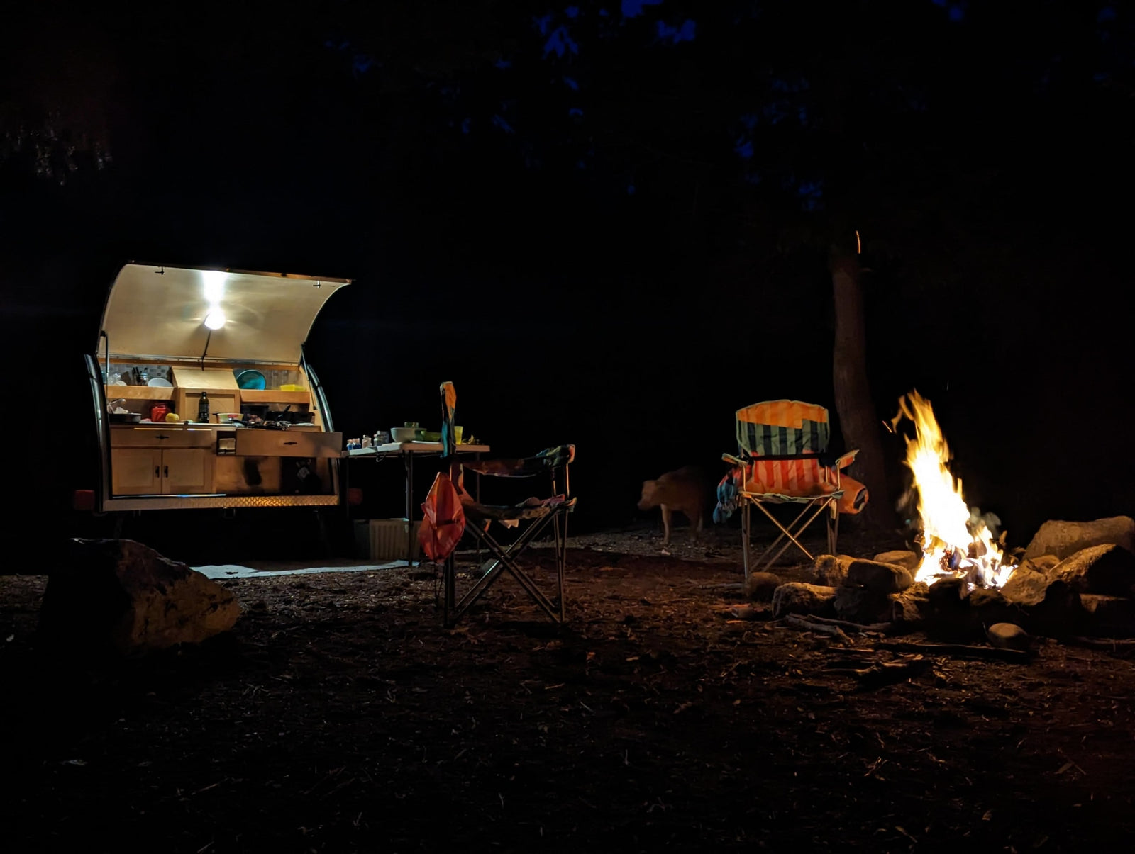  with a window overlooking a green field.|This RV rental offers a cozy camping experience: a comfy bed in a glowing teardrop trailer