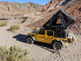 Bright yellow Jeep with deployed roof-top tent, ready for a rugged desert rv rental adventure. Ideal for off-grid camping.
