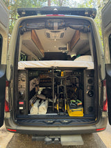 Adventure-ready RV rental: rear view of a camper van's smart gear storage, bike rack, and raised bed.