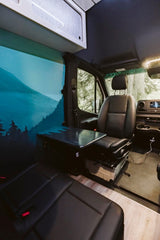 This RV rental's interior features a vibrant mountain mural, comfortable seating, and a practical fold-down table for travel.