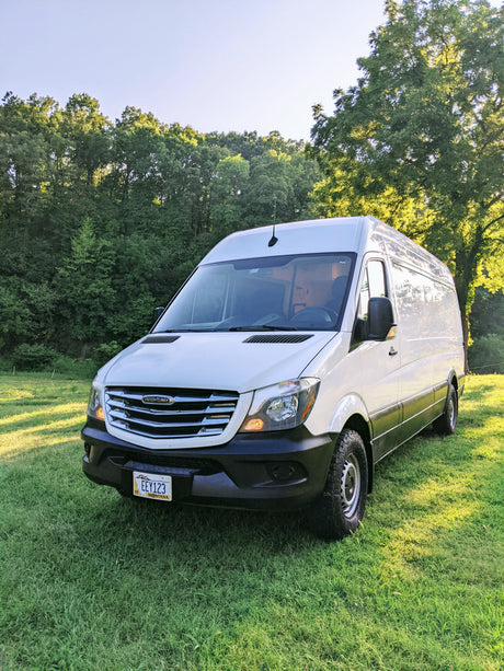 White Freightliner camper van on green grass. Ready for your next RV rental adventure.