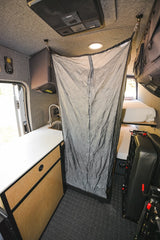RV rental interior with kitchen sink, deployable privacy curtain, and rear bunk beds.