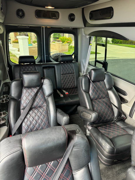 Luxurious rv rental interior: plush black leather seats with red diamond stitching, ample seating, and convenient amenities for travel.