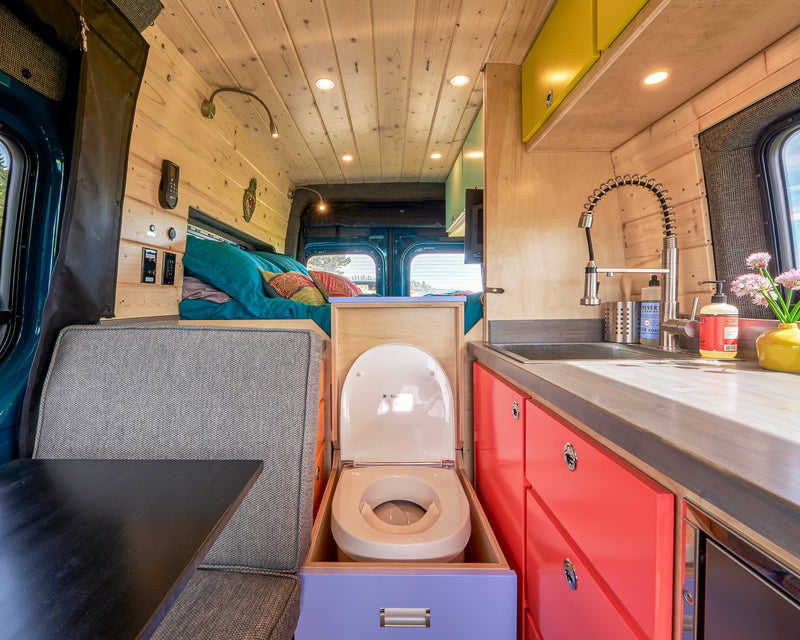 Modern RV rental interior: wood-paneled walls & ceiling, compact kitchen, hidden composting toilet, & cozy bed/dinette. — photo 3