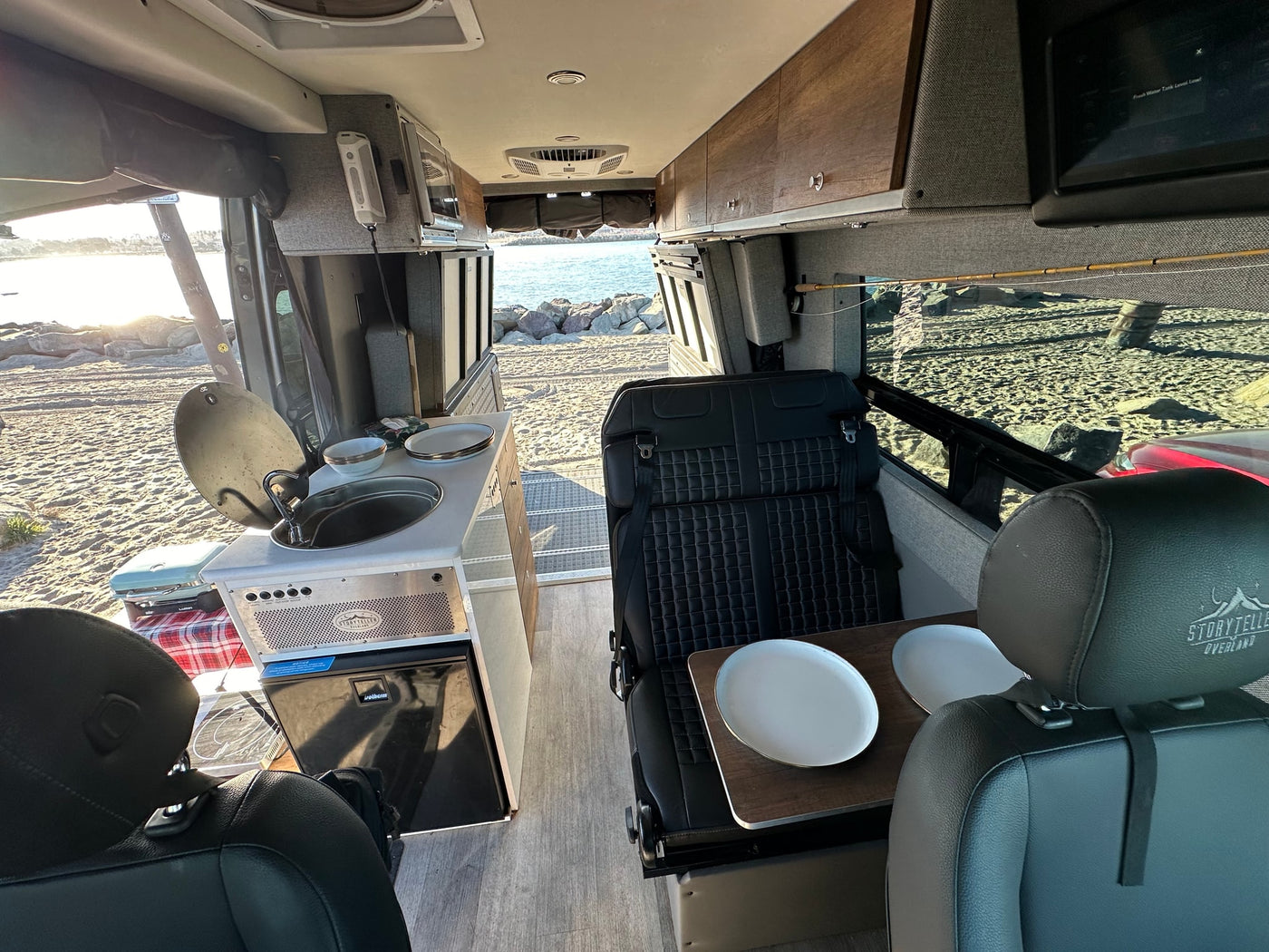 Explore with our RV rental: a Storyteller Overland camper van interior featuring kitchen, seating, and beach views. — photo 3