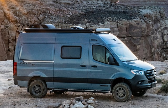 This rugged gray Mercedes-Benz Sprinter Revel 4x4 RV rental is parked in a scenic desert, ideal for off-road camping adventures.