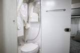 Clean rv rental interior featuring a compact shower and toilet area, with a glimpse of the comfortable bedroom.