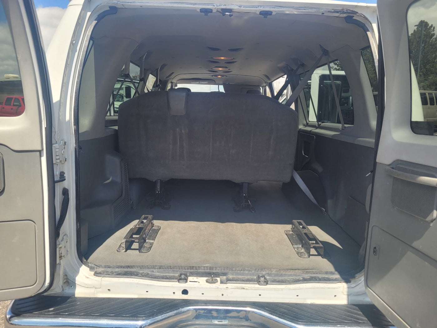 View of an RV rental van's open rear cargo area. Dark bench seat & floor mounts highlight flexible interior space for travel. — photo 4