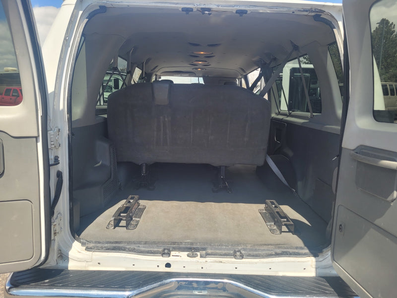 View of an RV rental van's open rear cargo area. Dark bench seat & floor mounts highlight flexible interior space for travel. — photo 4