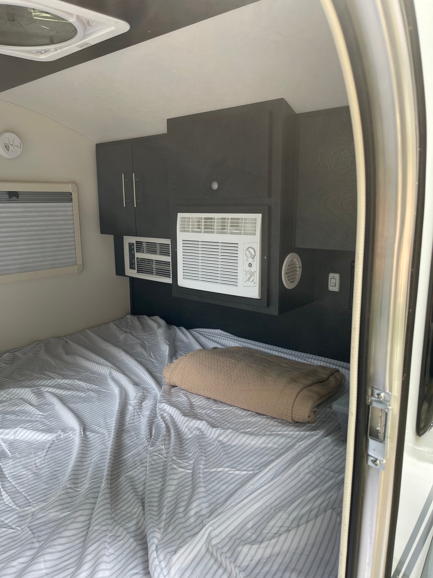 This RV rental interior features a cozy bed, dual AC units for climate control, and smart storage. Perfect for your trip.