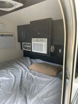This RV rental interior features a cozy bed, dual AC units for climate control, and smart storage. Perfect for your trip.