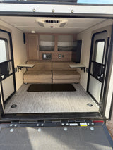 RV rental interior: convertible beds, ceiling AC, built-in storage, and a rear ramp door with floor tie-downs.