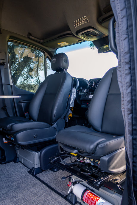 Interior of an **rv rental**, showing front seats, dashboard, overhead light controls, and a fire extinguisher.