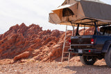 Jeep Gladiator with rooftop tent deployed in red rock desert, ready for your rugged RV rental adventure.