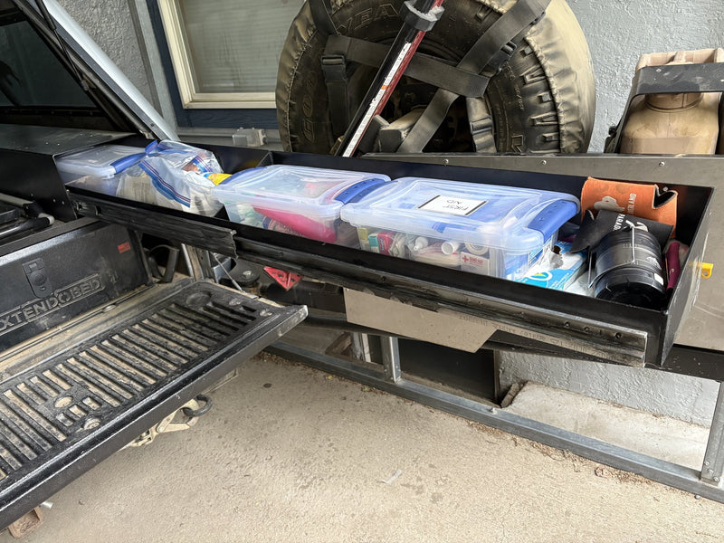 Long side drawer of the Extendobed system pulled open, loaded with clear storage bins including a first aid kit, next to the open tailgate — photo 4