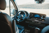 RV rental adventure awaits! Inside a Mercedes Sprinter van: dashboard, steering wheel, and a spacious view of the open landscape.