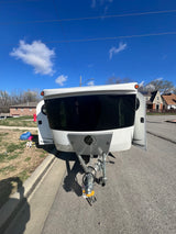 White Luna travel trailer, perfect for an rv rental, parked street-side under a sunny blue sky, ready for adventure.