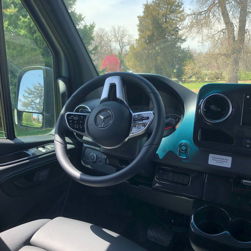 Interior shot of a Mercedes-Benz RV rental, highlighting the driver's modern steering wheel & dashboard controls. Trees visible outside. — photo 12