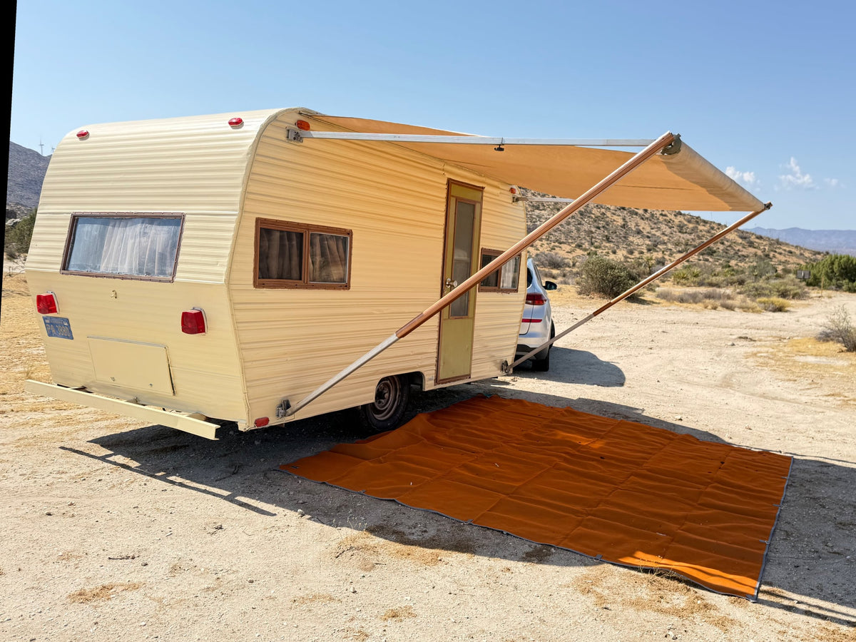 This vintage RV rental is set up for desert camping with its extended awning and ground mat