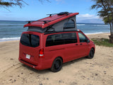 Red camper van (RV rental) with pop-top roof on a sandy Hawaii beach by the ocean. Ideal for island adventures.