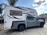 This grey Toyota Tundra, fitted with a white Lance truck camper, offers a robust RV rental option for your next adventure.