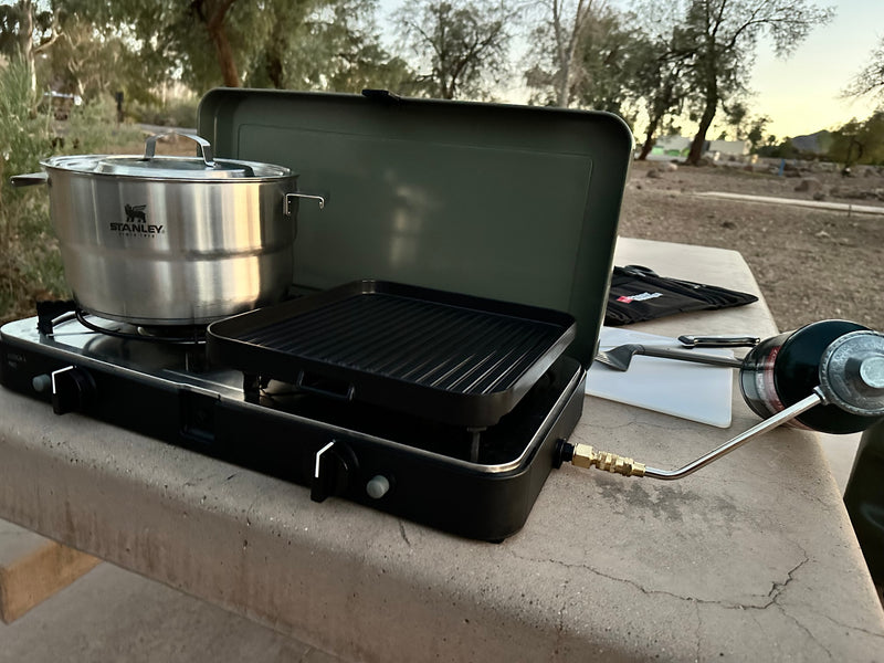 Preparing a meal on a dual-burner camping stove with a Stanley pot and grill, powered by propane, ideal for an RV rental trip. — photo 13