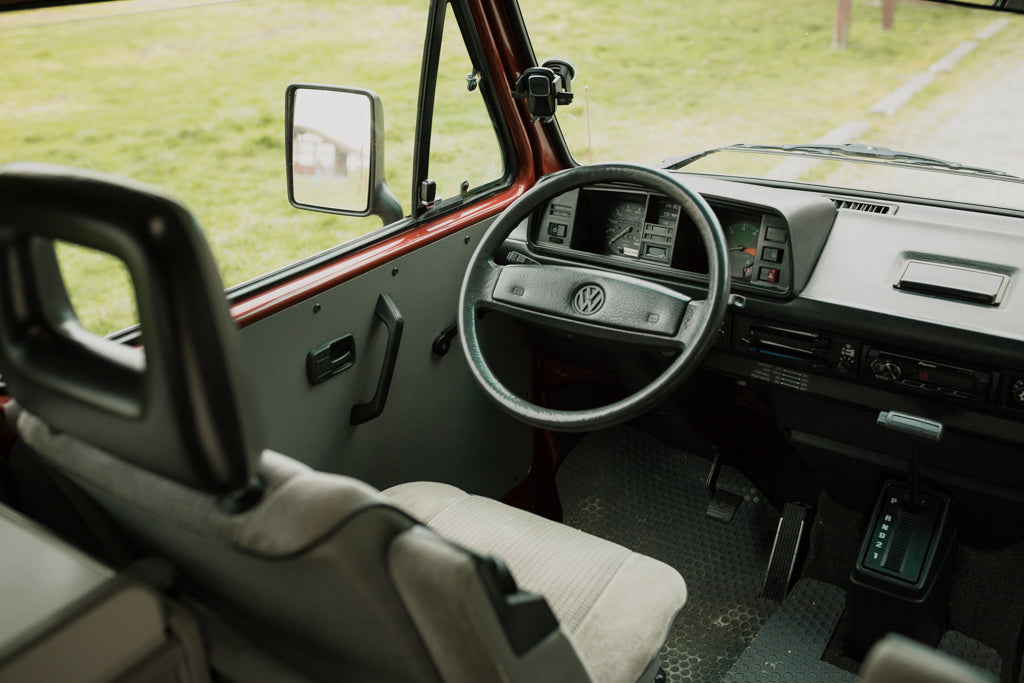 Classic VW van interior: steering wheel, dashboard, & automatic shifter for your RV rental adventure.