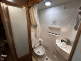 Inside a compact RV rental bathroom: features a toilet with an open lid, small corner sink, and shower area with curtain.