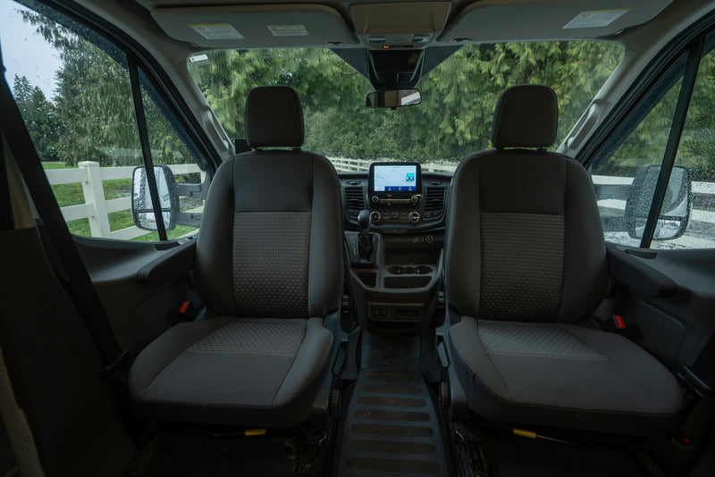 Inside an RV rental: front cabin with seats, dashboard display, and wet windshield view. — photo 13