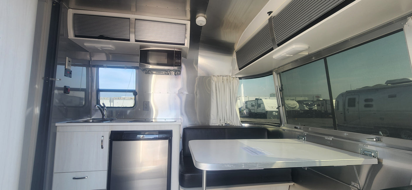Step inside this modern RV rental! A well-equipped kitchen, comfy dining booth, & sleek Airstream-style interior await your travel.