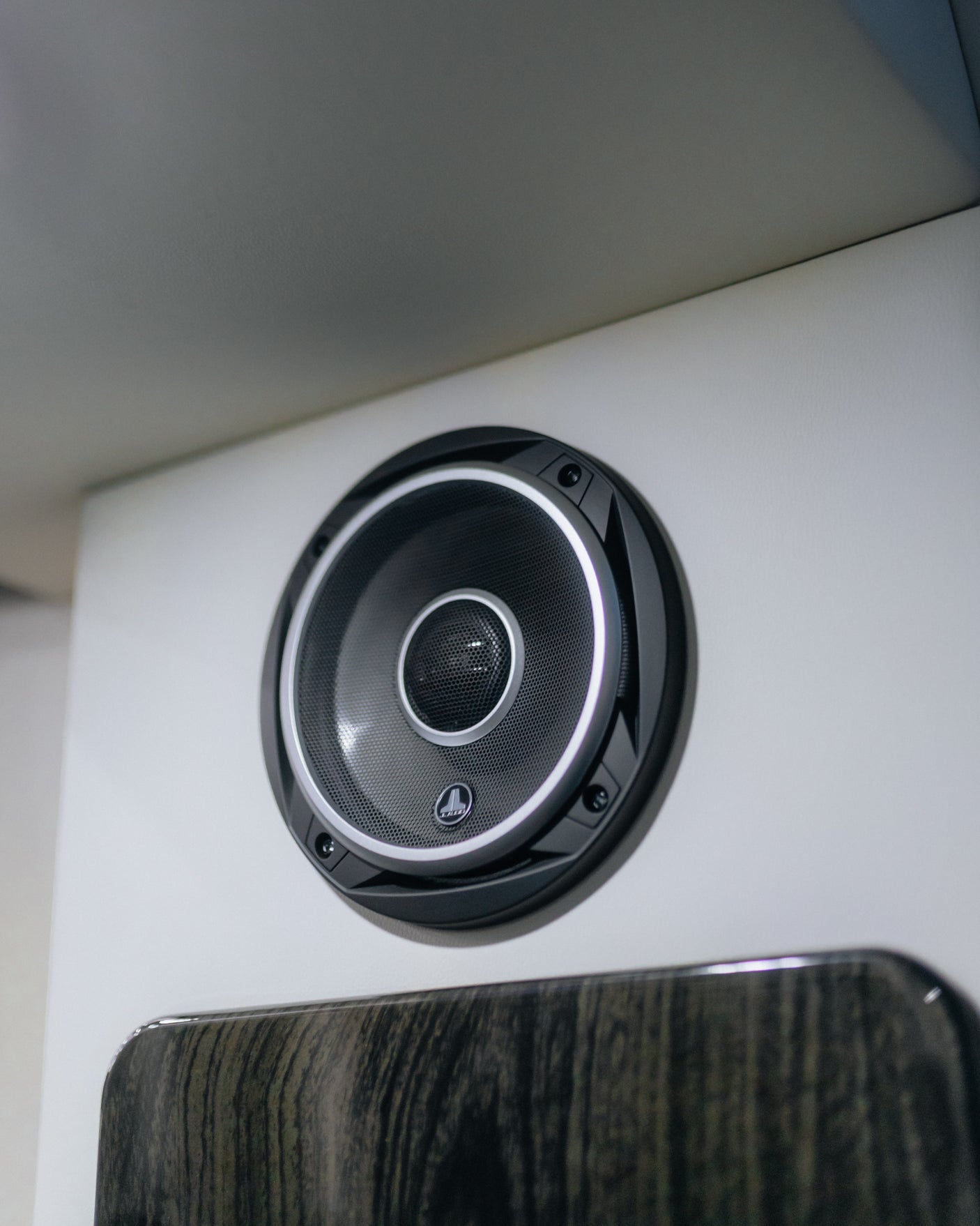 Close-up of a JL Audio speaker on a white panel in an RV rental, offering crisp audio.