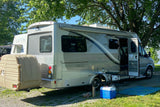 Scenic RV rental campsite with a Leisure Travel Vans Unity, outdoor table, and cooler setup by the water.