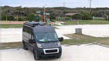 Gray Ram ProMaster RV rental parked at a serene outdoor park with a playground and picnic area.