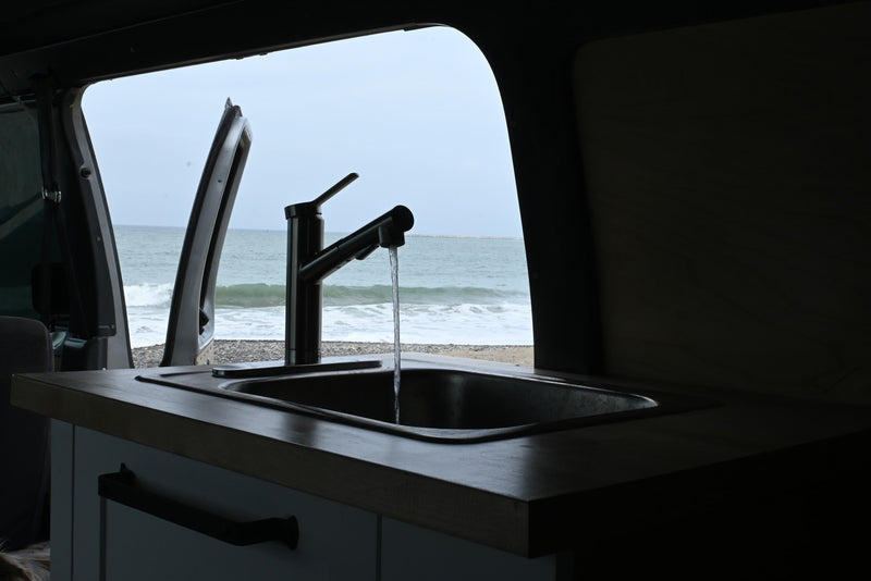 Enjoy ocean views from your RV rental kitchen! Water runs in the sink, with a beach and waves visible outside. — photo 7