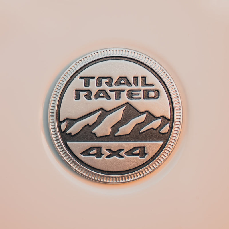 Close-up of a silver 'TRAIL RATED 4x4' vehicle badge, essential for rugged rv rental adventures. Shows mountains & text. — photo 13