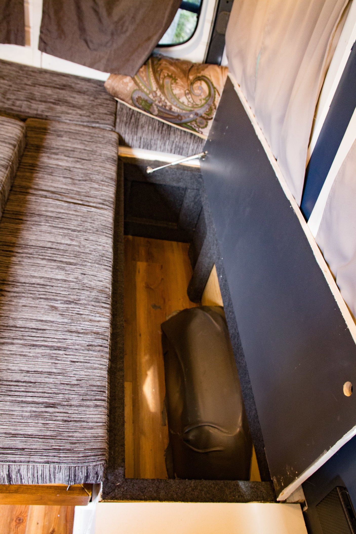 RV rental: Clever under-seat storage in a camper van, revealing a hidden water tank. Perfect for maximizing small spaces.