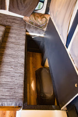 RV rental: Clever under-seat storage in a camper van, revealing a hidden water tank. Perfect for maximizing small spaces.