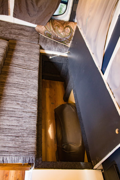 RV rental: Clever under-seat storage in a camper van, revealing a hidden water tank. Perfect for maximizing small spaces.