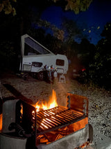 Cozy night camping with an RV rental: roaring campfire, pop-up camper, and starry sky.