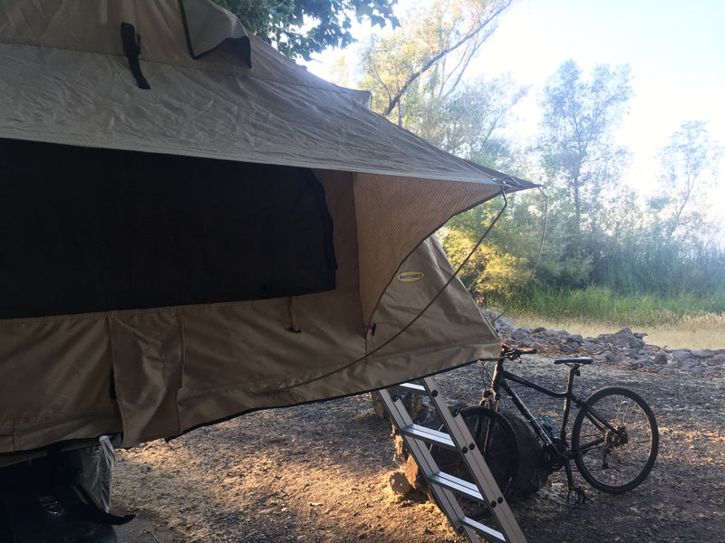 Rear quarter view of the canopy showing large blacked-out mesh windows, awning panel and the ladder resting on the ground — photo 6