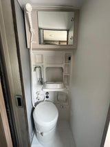 Compact RV rental wet bath featuring a toilet, sink, and shower. Designed for efficient use of space on your trip.