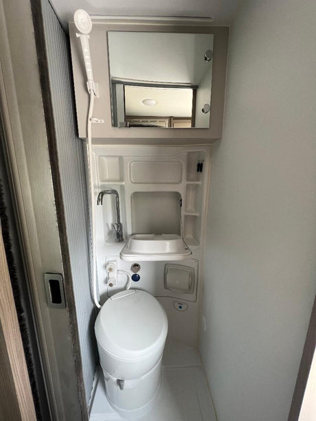 Compact RV rental wet bath featuring a toilet, sink, and shower. Designed for efficient use of space on your trip.
