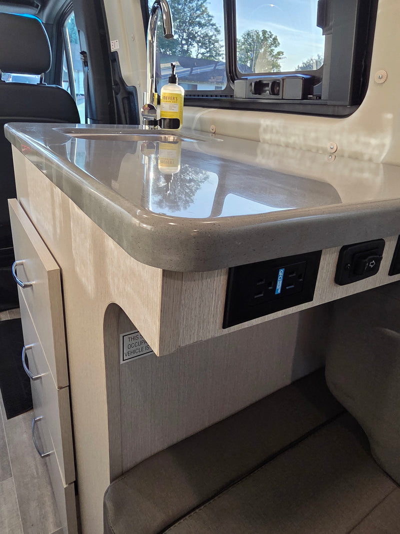 RV rental: Clean kitchenette features a sleek sink, chrome faucet, power outlets, and light wood cabinetry for travel. — photo 12