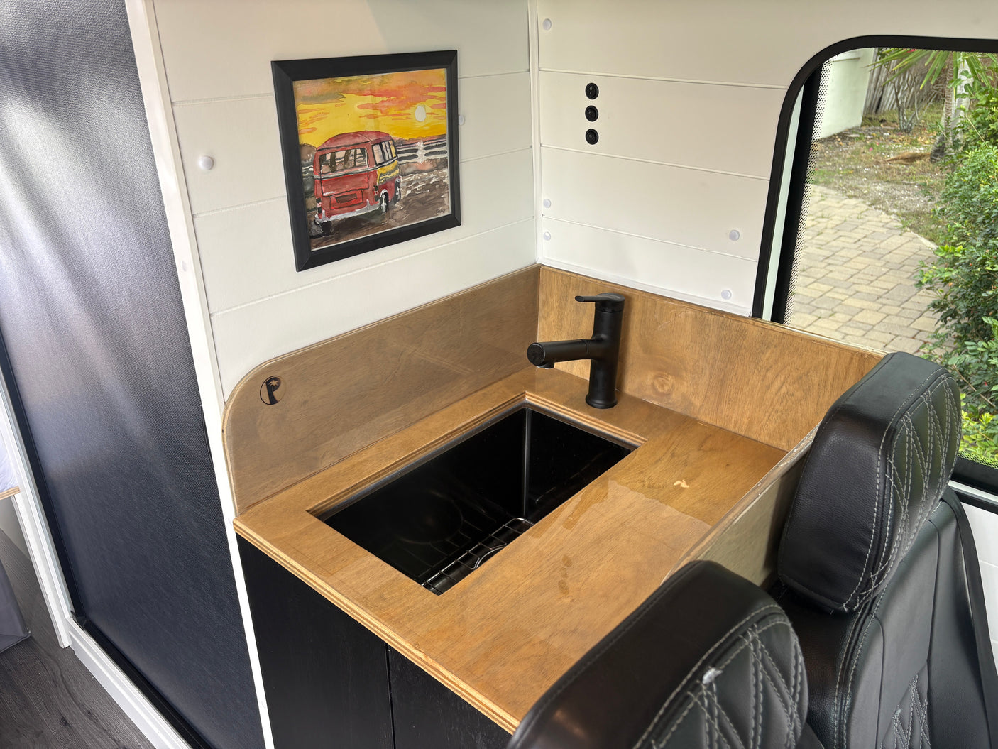 RV rental: Modern sink, wood counter, shiplap walls, and a window view in this camper van kitchen.