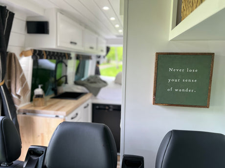 Spacious RV rental interior with kitchen, comfy seats, and a "sense of wonder" sign. Perfect for adventure!