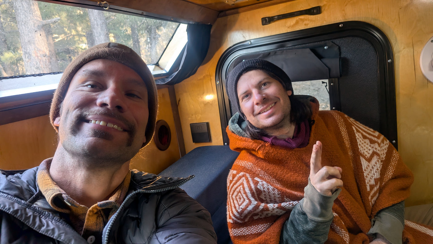 Two smiling men in a wood-paneled RV rental, cozy inside with a window view of trees, ready for a travel adventure. — photo 8