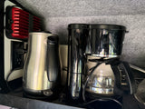 Essential RV rental kitchen appliances: a shiny kettle, coffee maker, and a powerful cell signal booster.