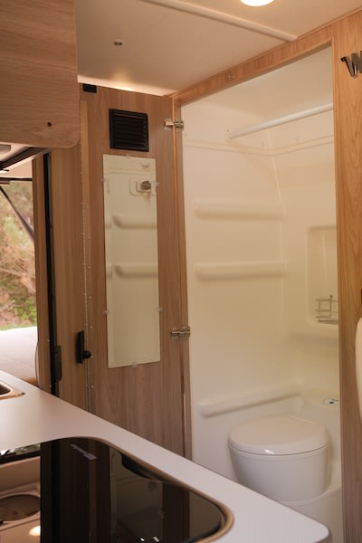  and adjacent bed.|Inside RV rental: ladder accesses elevated sleeping area. Includes smoke detector and window.|Experience serene mornings in your RV rental! A cozy bed faces a rounded — photo 9