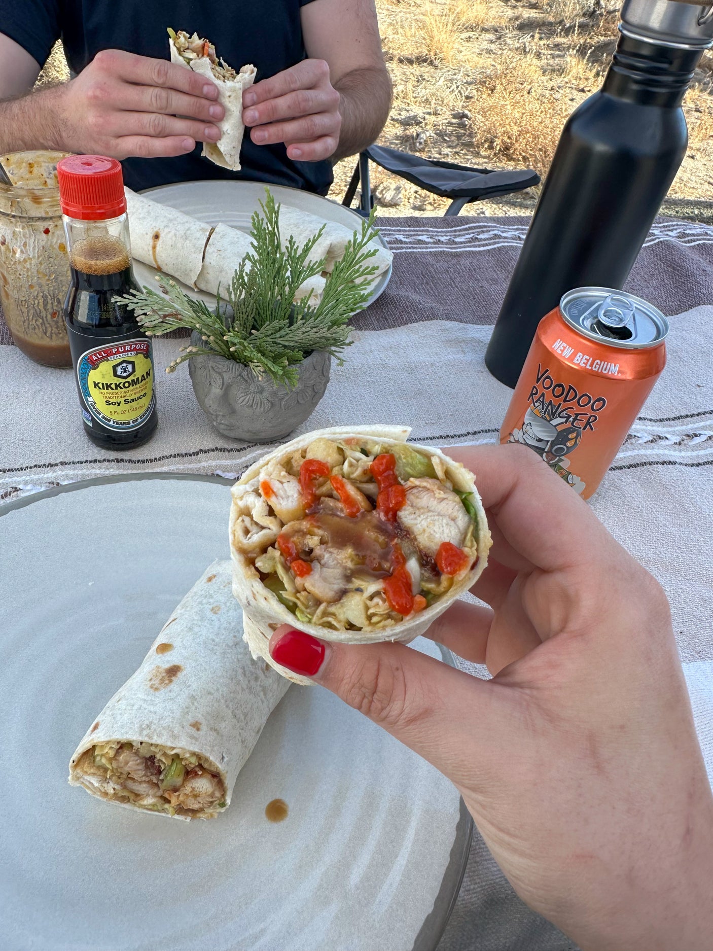 Delicious chicken wraps with chili sauce, drinks, and soy sauce outdoors. Perfect for an rv rental trip!