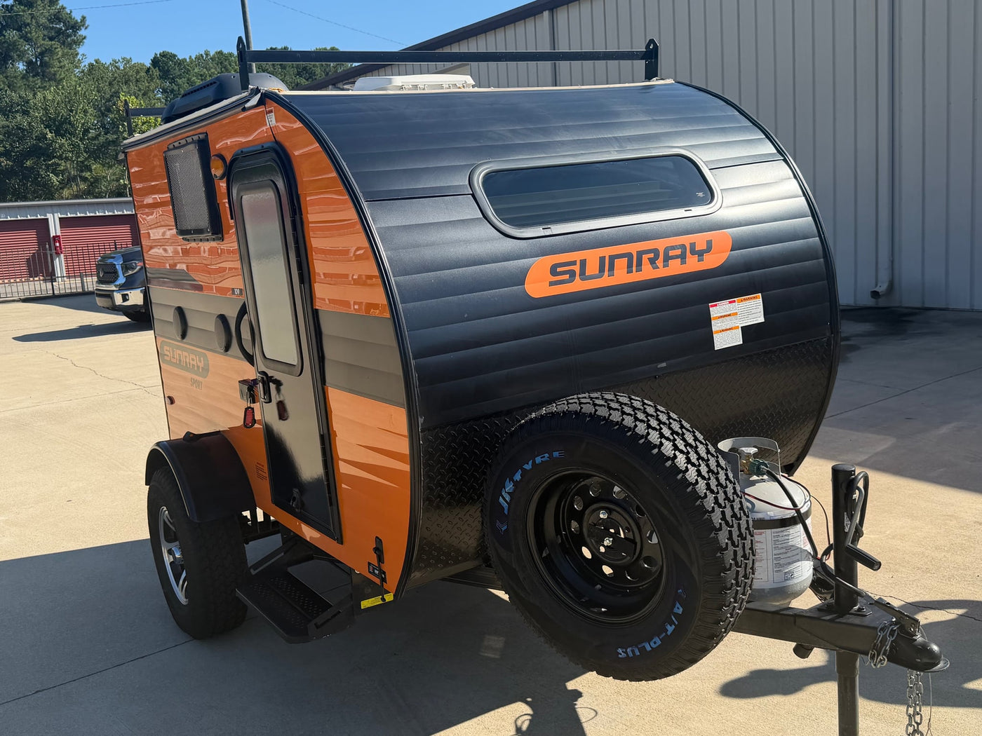  ready for your next travel or camping adventure.|This orange and black Sunray Sport teardrop RV rental is a compact camper with a roof rack and front-mounted spare tire.|This bright orange Sunray Sport teardrop trailer is ready for your RV rental adventure — photo 2